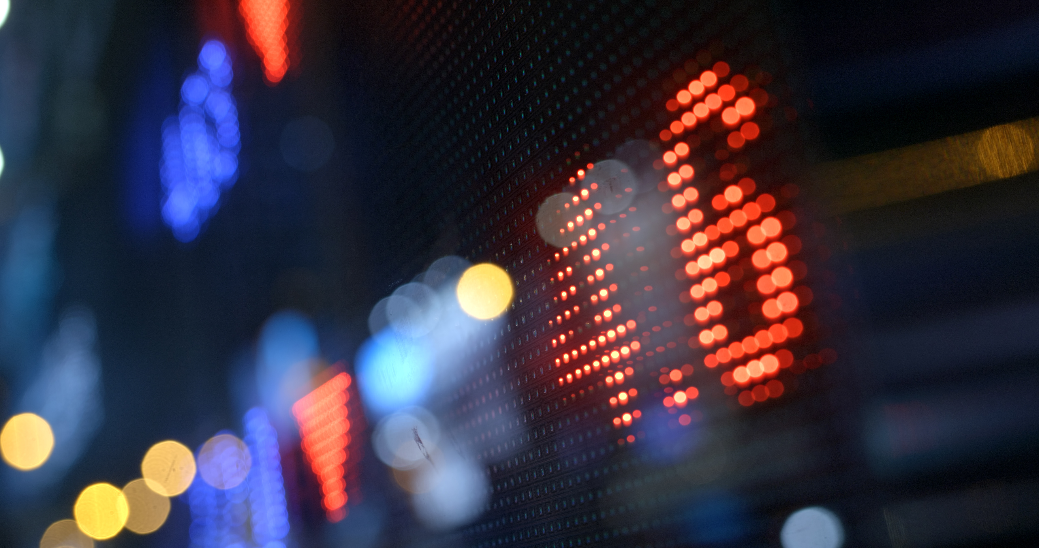 Electronic stock market ticker display with red and blue lights at night